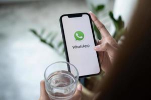 chiang mai, tailandia - 30 de marzo de 2022 hombre sosteniendo un iphone y una tienda de aplicaciones abierta buscando el servicio de internet social whatsapp en la pantalla. iphone fue creado y desarrollado por apple inc.. foto