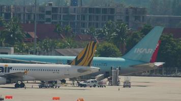 PHUKET, THAILAND DECEMBER 6, 2016 - View of Phuket airport apron with TigerAIr Airbus 320 9V TAE and Ikar Boeing 767 VP BOY loading for departure video