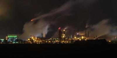 paisaje industrial nocturno contaminación ambiental residuos de central térmica. grandes tuberías de la planta empresarial de la industria química foto
