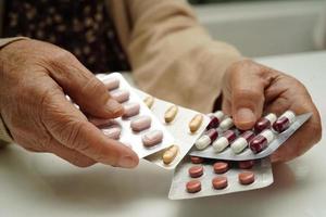 Asian elderly woman holding pill drug in hand, strong healthy medical concept. photo