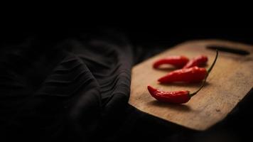 chili in the cutting board with black background texture photo