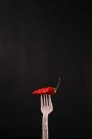 premium chili in the fork with black background photo