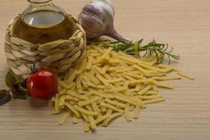 Raw pasta on wooden background photo