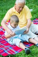 abuelo y niño en el parque usando tableta foto