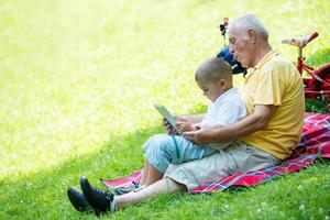 grandfather and child in park using tablet photo