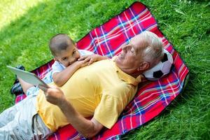 grandfather and child in park using tablet photo