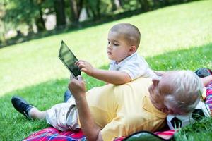 grandfather and child in park using tablet photo