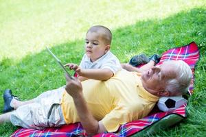 grandfather and child in park using tablet photo