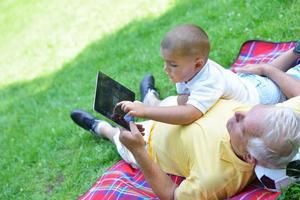 grandfather and child in park using tablet photo