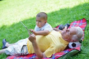 grandfather and child in park using tablet photo