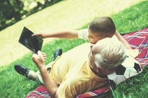 grandfather and child in park using tablet photo