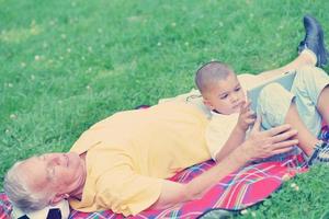 grandfather and child in park using tablet photo