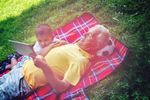 grandfather and child in park using tablet photo