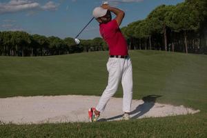 golfer hitting a sand bunker shot photo