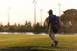 golfer  walking and carrying golf  bag at beautiful sunset photo