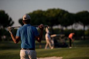 golfista desde atrás en el campo mirando al hoyo en la distancia foto