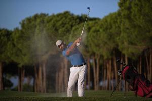 golfer hitting a sand bunker shot on sunset photo