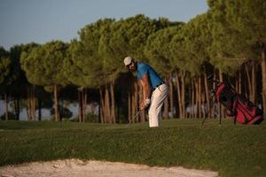 golfer hitting a sand bunker shot on sunset photo