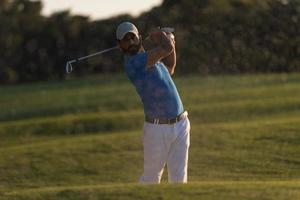 golfista golpeando un tiro de búnker de arena al atardecer foto