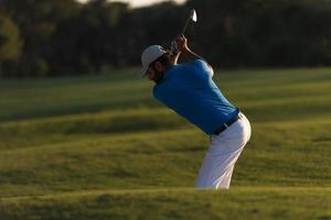 golfista golpeando un tiro de búnker de arena al atardecer foto