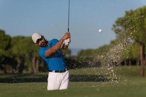 pro golfer hitting a sand bunker shot photo