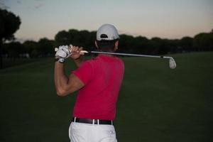 golfer hitting a sand bunker shot on sunset photo