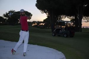 golfer hitting a sand bunker shot on sunset photo