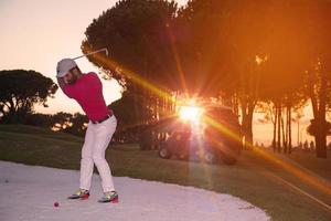 golfista golpeando un tiro de búnker de arena al atardecer foto