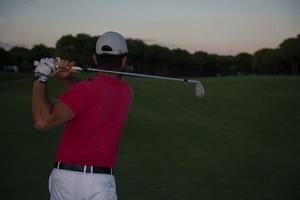 golfer hitting a sand bunker shot on sunset photo