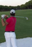 golfer hitting a sand bunker shot on sunset photo