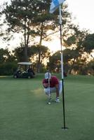 jugador de golf apuntando tiro perfecto en la hermosa puesta de sol foto