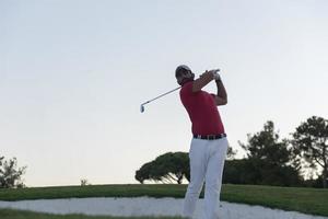 golfer hitting a sand bunker shot on sunset photo