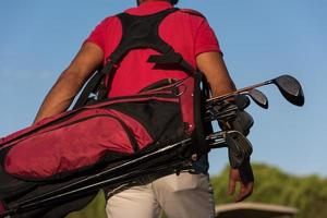 close up of golfers back while   walking and carrying golf  bag photo