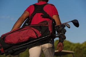 close up of golfers back while   walking and carrying golf  bag photo