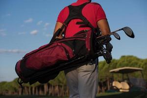 close up of golfers back while   walking and carrying golf  bag photo