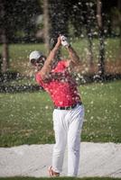 golfista golpeando un tiro de búnker de arena foto