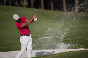 golfista golpeando un tiro de búnker de arena foto