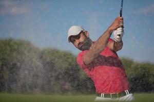 golfer hitting a sand bunker shot photo