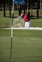 golfer hitting a sand bunker shot photo
