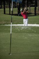 golfer hitting a sand bunker shot photo