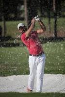 golfista golpeando un tiro de búnker de arena foto