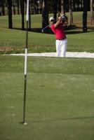 golfista golpeando un tiro de búnker de arena foto