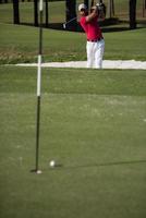 golfer hitting a sand bunker shot photo