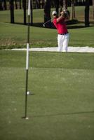 golfer hitting a sand bunker shot photo