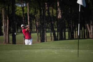 golfer hitting a sand bunker shot photo