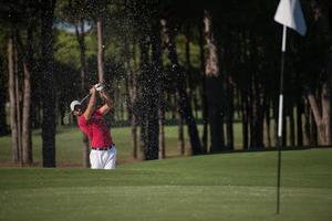 golfer hitting a sand bunker shot photo