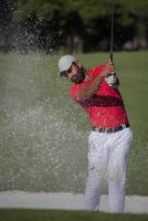 golfer hitting a sand bunker shot photo