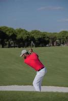 golfista golpeando un tiro de búnker de arena foto