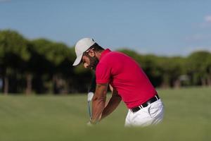 golfer hitting a sand bunker shot photo