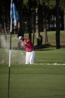 golfer hitting a sand bunker shot photo